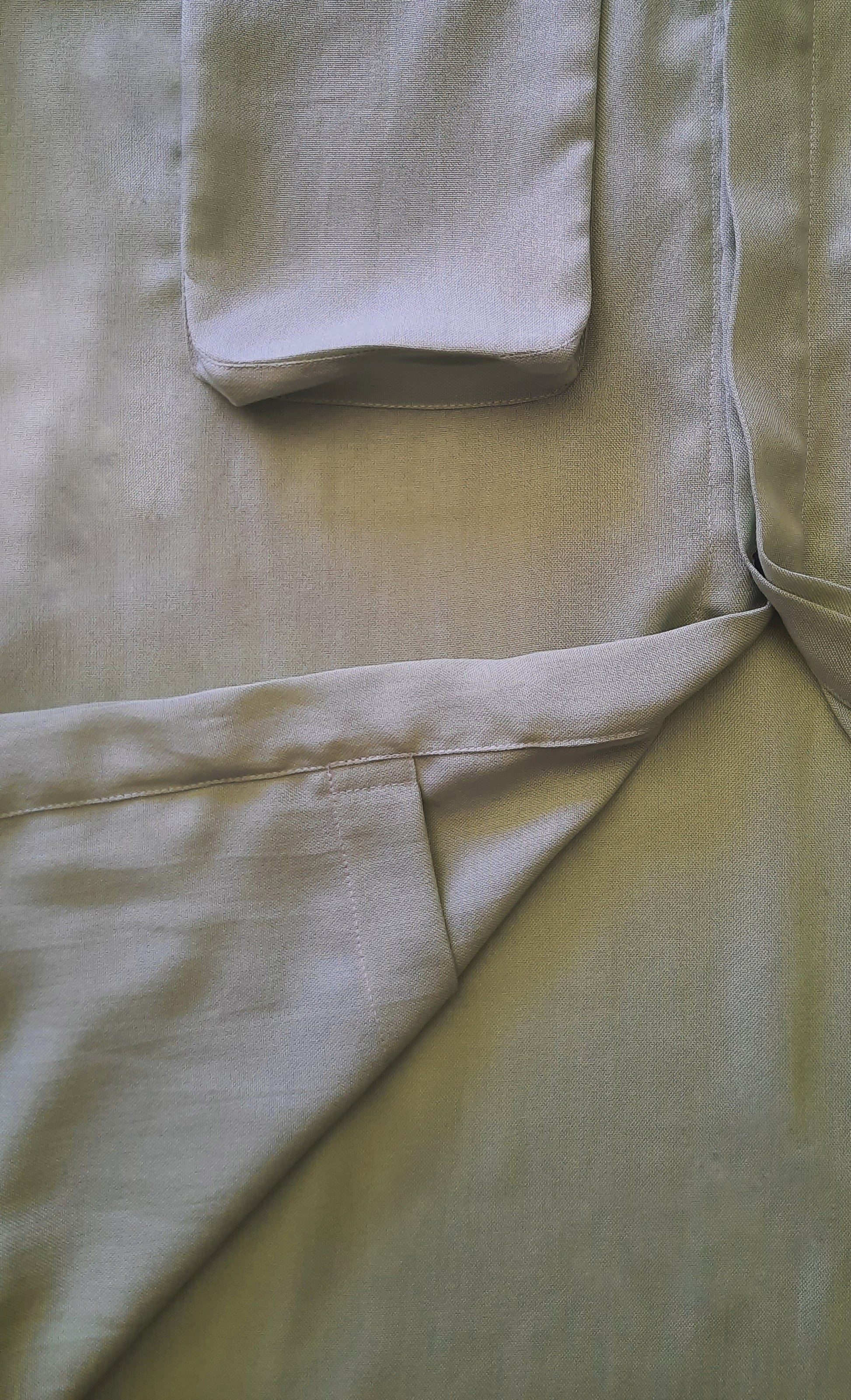 a closeup image of a green shirt with the front folded up to see the internal pocket. 